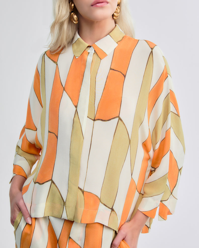 Camisa de manga longa ampla em seda, estampa geométrica em laranja, bege e verde.